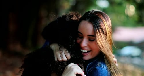 Two Cheerful Women Hugging in the Sunlit Outdoors