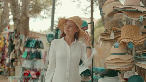 Mujer joven prueba sombreros en la tienda turística