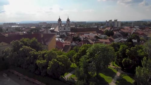 Turning and ascending drone shot over a city with churches and lush green trees