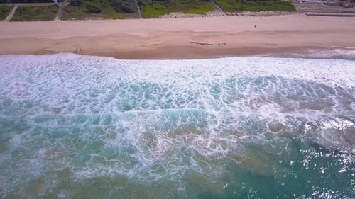 Blick von oben auf türkisfarbenes Wasser. Filmmusik Luftaufnahme großer Meereswellen, die am Ufer zusammenbrechen