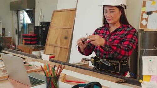 Woman in a Red Plaid Shirt Sharpening a Pencil with a Utility Knife in a Woodworking Workshop Ideal