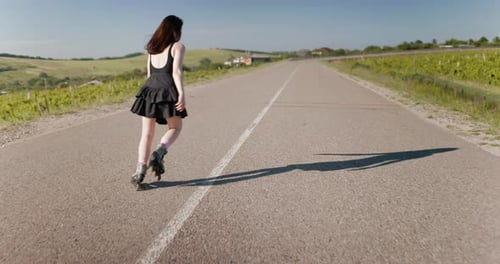 Young Woman Roller Skating Down Rural Road