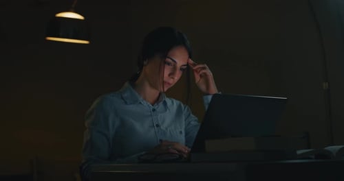 Slow motion of a young beautiful business woman is working with a computer in the evening in a off