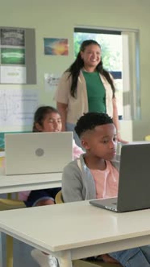 Vertical video: Reacting to teacher in green tee entering, front boy on laptop in class for lesson