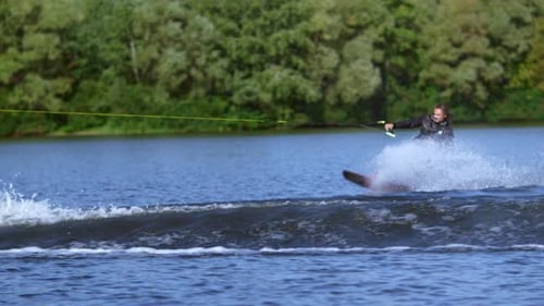 Young man wakeboarding behind motorboat on lake enjoying summer vacation