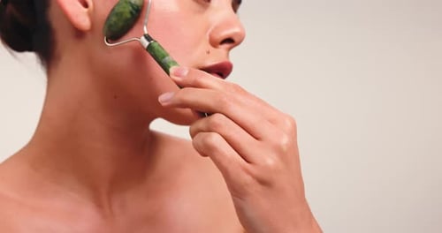 Jade roller, skincare and woman in studio for facial routine, anti aging massage and smooth skin