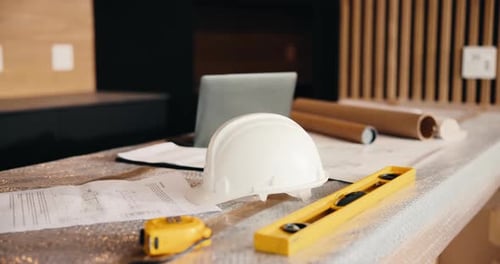 Laptop, helmet and building with construction documents for architecture, maintenance or planning