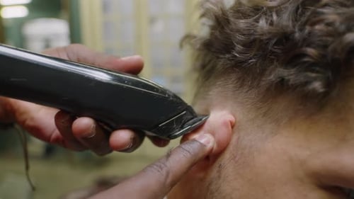 Hands of Barber rasieren sich hinter den Ohren mit einem Haarschneider