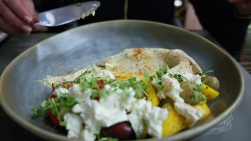 Femme en gros plan mangeant de l'humus avec du fromage feta et des légumes dans un restaurant