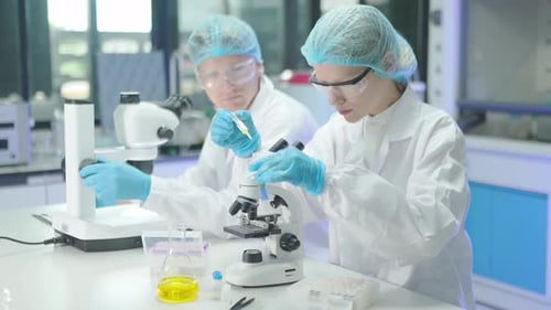 Scientists Working with Microscopes and Liquid Samples