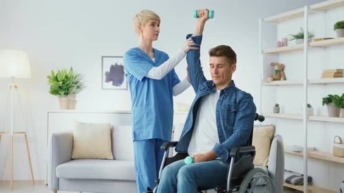 Physical Therapist Assists Man in Wheelchair with Exercise