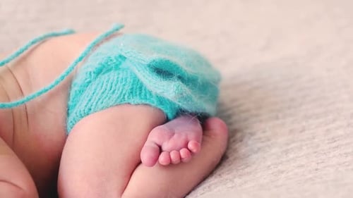 Baby Feet in Blue Knitted Diaper on Blanket