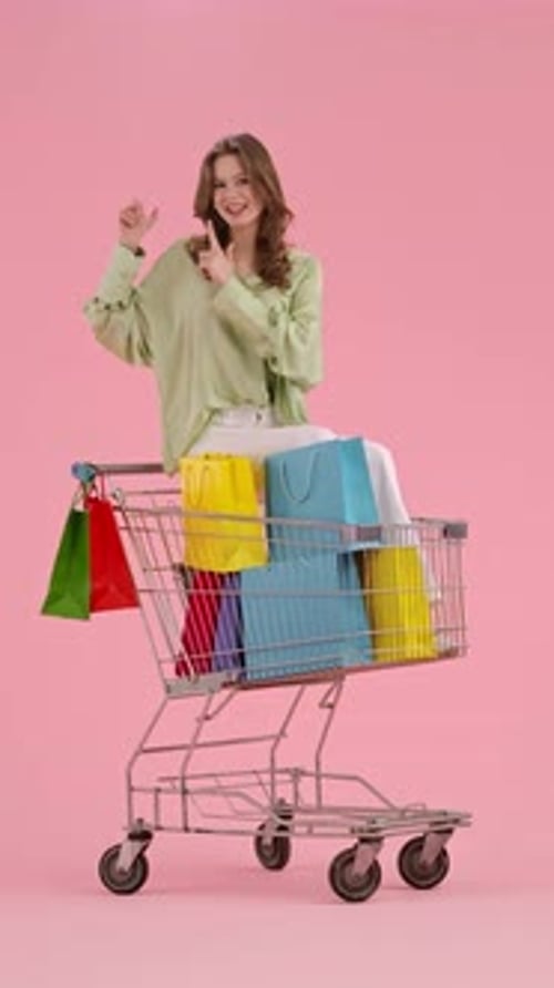 Woman Sits in Shopping Cart with Shopping Bags
