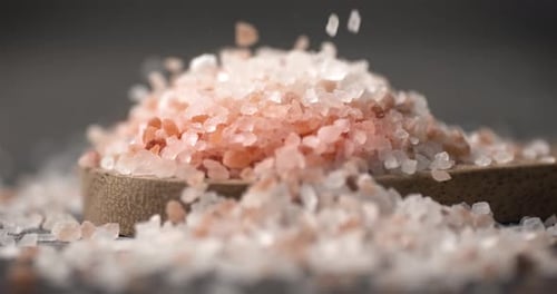 Pink Salt Crystals Falling onto a Wooden Spoon
