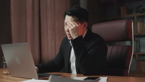 Frustrated Businessman at Desk with Laptop