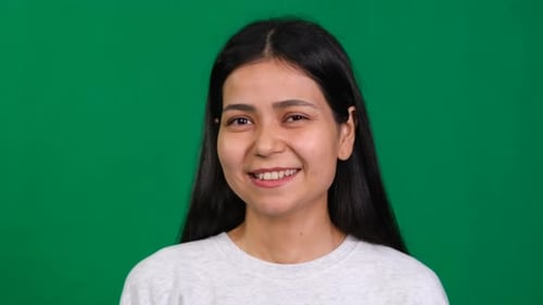 Young Woman in a Studio Portrait Exudes Optimism with a Playful Wink Her Friendly Expression and