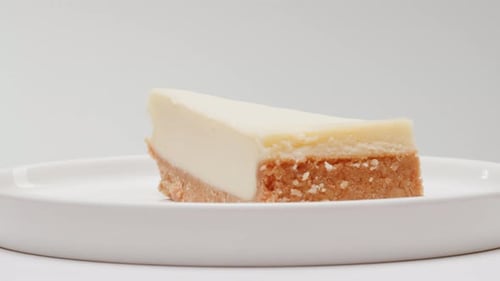 Rotating Slice of Delicious Cheesecake on White Plate