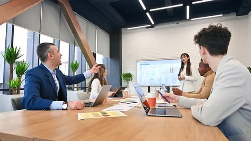 Female team leader at business meeting in an office, discussing business affairs with workers using