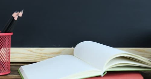 Pencils books and apple slide across school desk