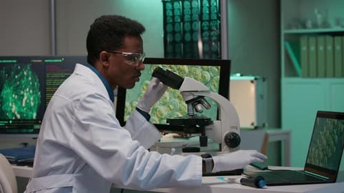 Researcher Examining Cells under Microscope and Using Smart Software on PC