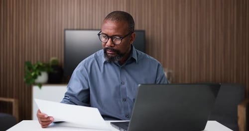 Black man, documents and finance with laptop for corporate analysis, budget or expenses in office