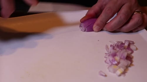 Cutting onion with a knife on wooden table