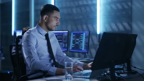 Controlador técnico profesional con colegas en sus estaciones de trabajo. Están en la sala de monitoreo