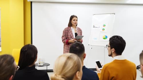 Business Woman Coach Trainer Presents a Report Shows Diagrams on Flip Chart in Conference Hall