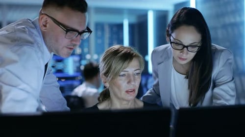 Ein Team von Systemtechnikern diskutiert über den Überwachungsraum. Im Hintergrund Leute, mit denen gearbeitet
wird