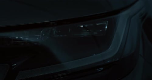 Close up of details of switched on headlights of anonymous prestigious luxury modern car. Shot in