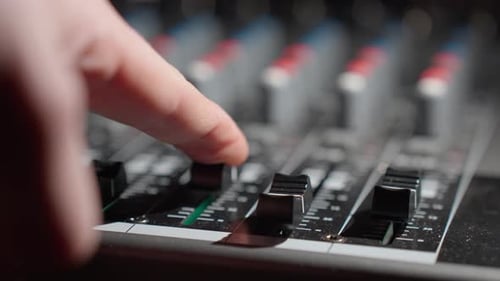 Man's finger increase the volume on the sound control panel mixer - close-up