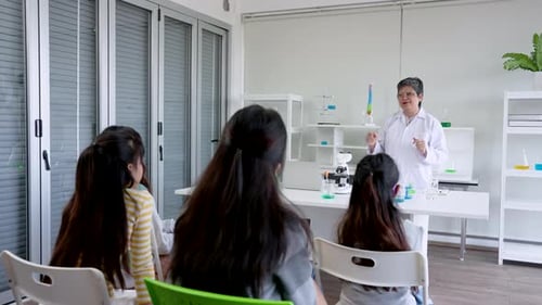 Elderly Asian female teacher is standing teaching students in front class in science room, school ch