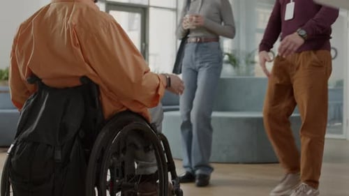 Man in Wheelchair High Fives Coworkers at Office