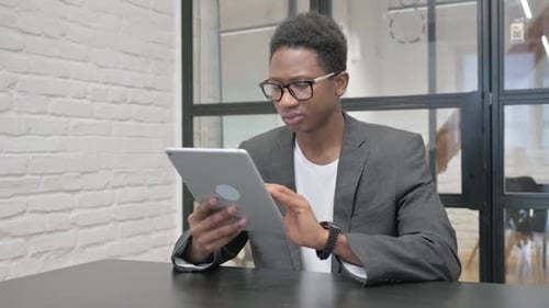 Young African Man Using Digital Tablet in Office