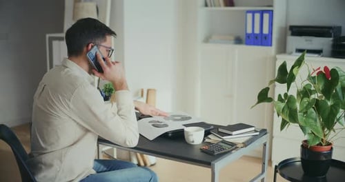 Man On Phone Reviews Business Data at Desk