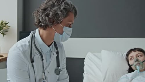 Doctor Attends Young Adult Patient in Hospital Bed