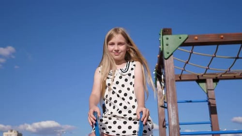 Child Girl Rides on a Swing at the Playground