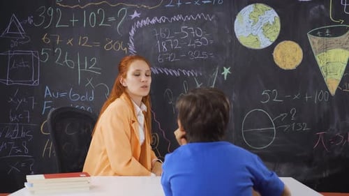Teacher Explains Math to Student at Classroom Table
