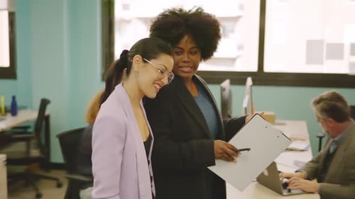 Young Women Discuss Documents in Modern Office
