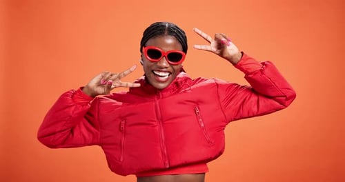 Happy, black woman and face with peace sign in fashion for style on a orange studio background