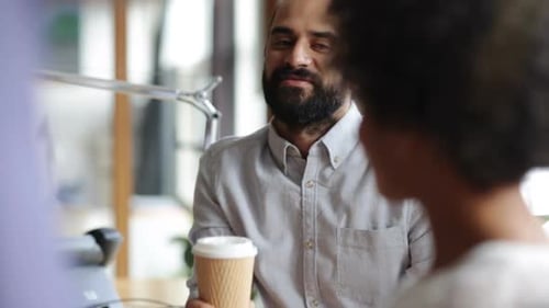Happy multiethnic business team chatting over coffee at break in modern office