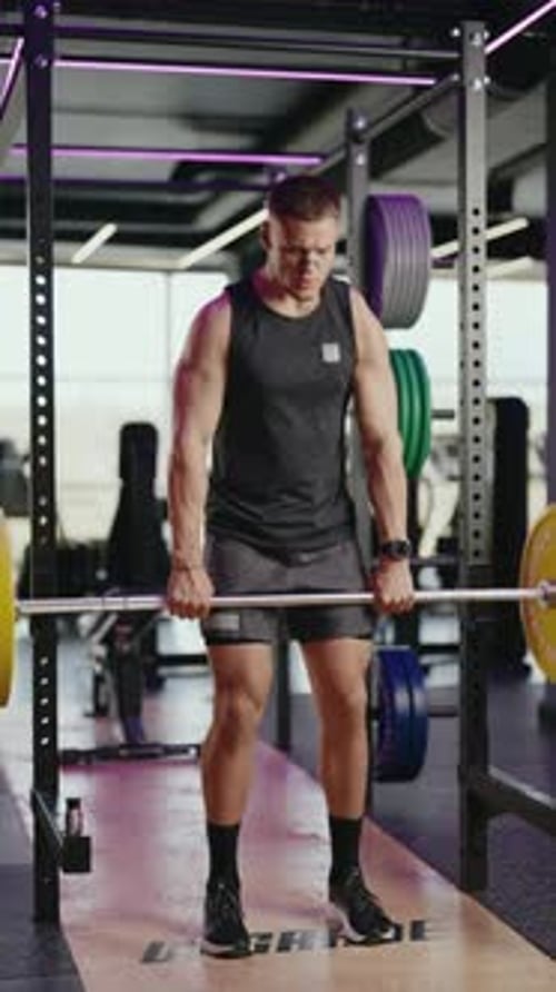 Muscular Man Performing Deadlifts in Modern Gym with Neon Lighting