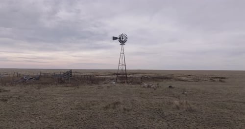 Rustic Texas windmill in an open prairie under a cloudy sky, evoking solitude