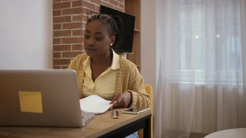 Woman Typing on Laptop and Reviewing Papers at Desk