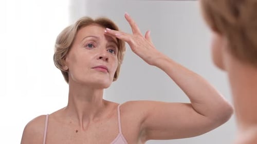 Woman Examining Face in Mirror