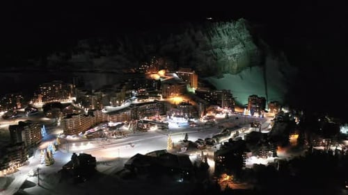 Christmas winter ski resort at night, ski run and hotel lights, aerial