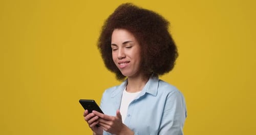Happy Woman Using Cell Phone on Yellow Background