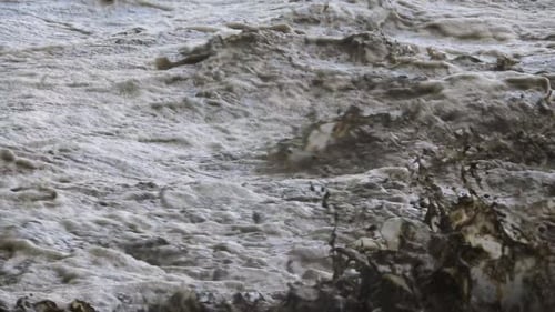 Hochauflösender Clip von schlammigem, wirbelndem Wasser, das alles mitnimmt, was sich ihm in den Weg stellt. Naturkatastrophe, Überschwemmung