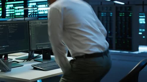 Man Works with Code in Dark Data Center