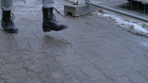 man walks on snowy road and cleans boots by stomping